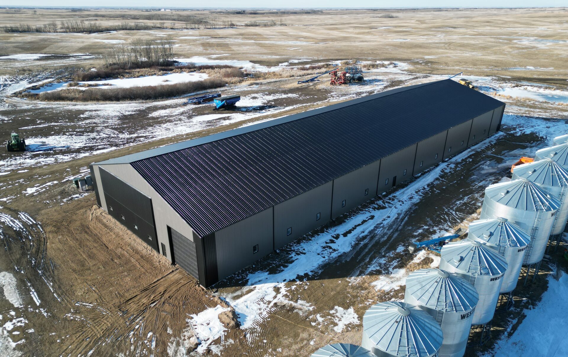 Large building with grain bins to the left and groomed landscape